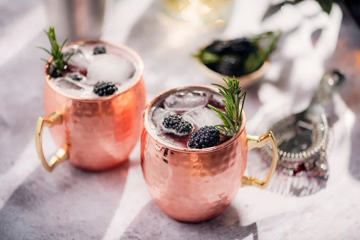 Blackberry Rosemary Mule Mocktail served in copper mugs with fresh blackberries, rosemary sprigs, lime, ginger beer, and crushed ice.