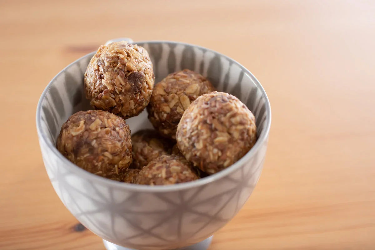 Oat-based energy balls in patterned bowl on wooden table, ideal for CBD or THC infusion