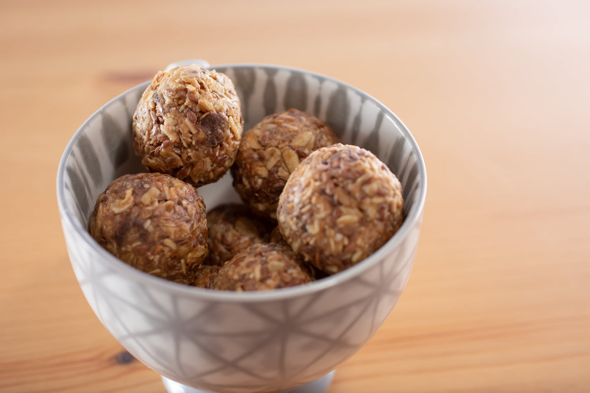 Oat-based energy balls in patterned bowl on wooden table, ideal for CBD or THC infusion