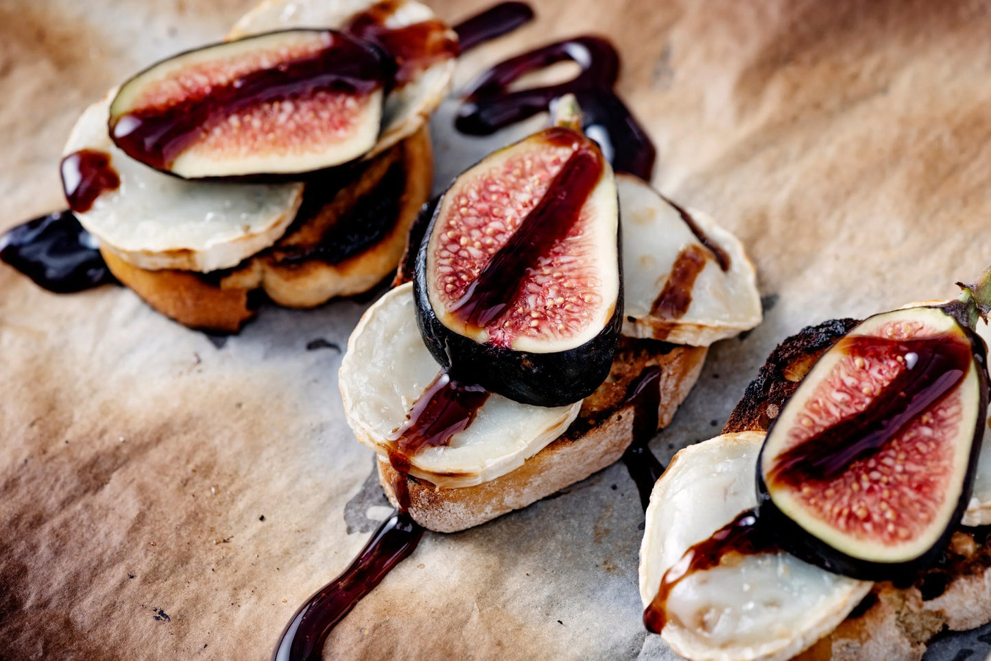 Crostini with fresh figs, goat cheese, and balsamic glaze on parchment paper