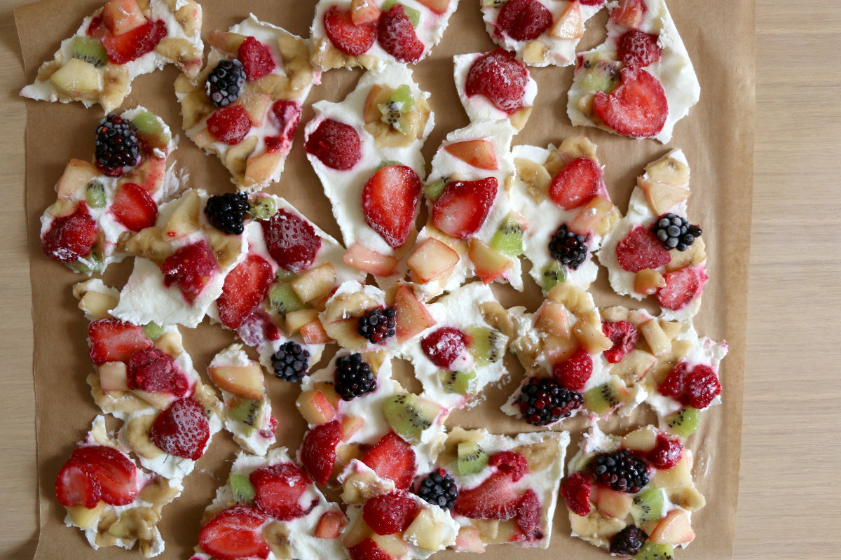 Fruit-topped yogurt bark with strawberries, kiwi, and blackberries on parchment paper