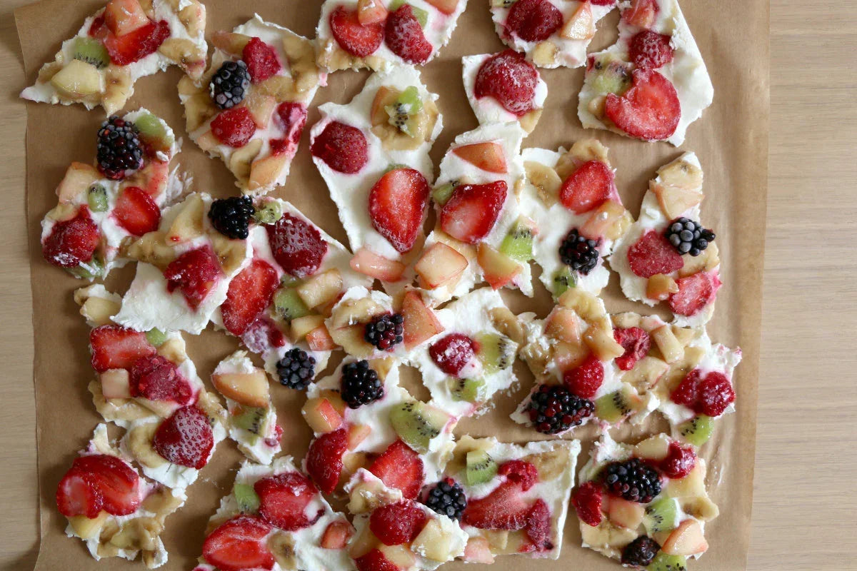 Fruit-topped yogurt bark with strawberries, kiwi, and blackberries on parchment paper