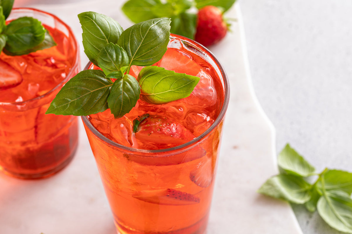 Strawberry Basil Spritz served over ice with fresh strawberries and basil garnish.