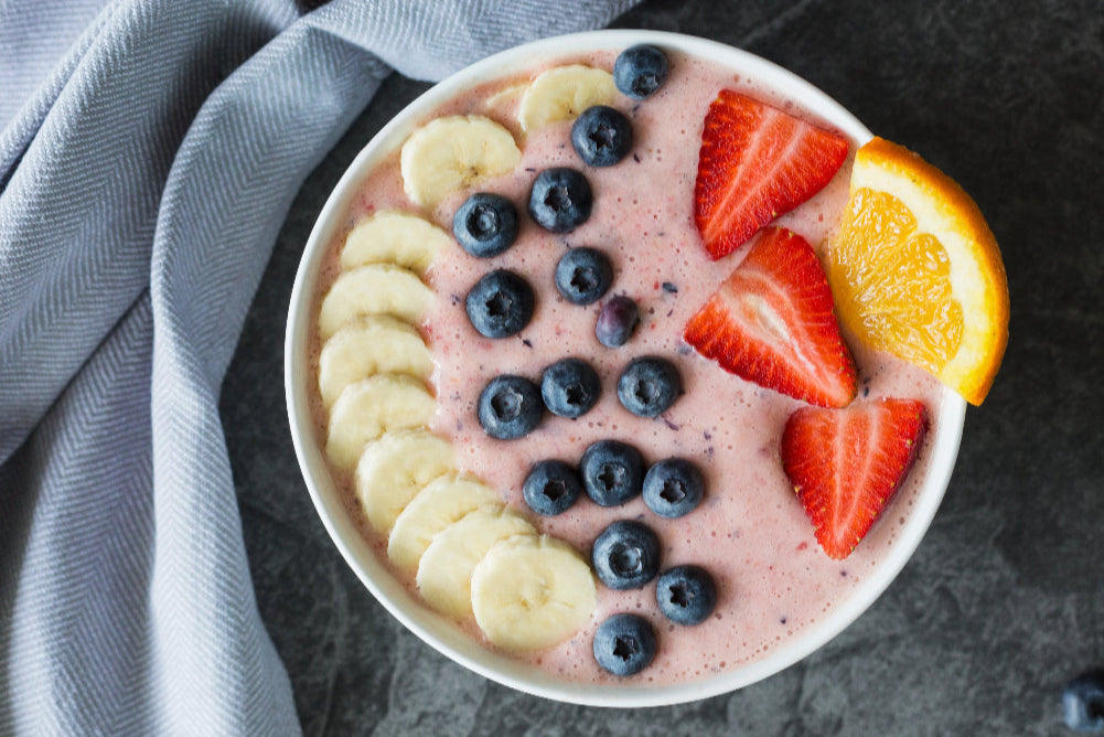 Infused yogurt bowl with strawberries, blueberries, and bananas on a dark surface