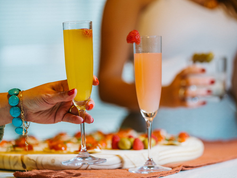 Two glasses of champagne with fruit on a table, blurred background