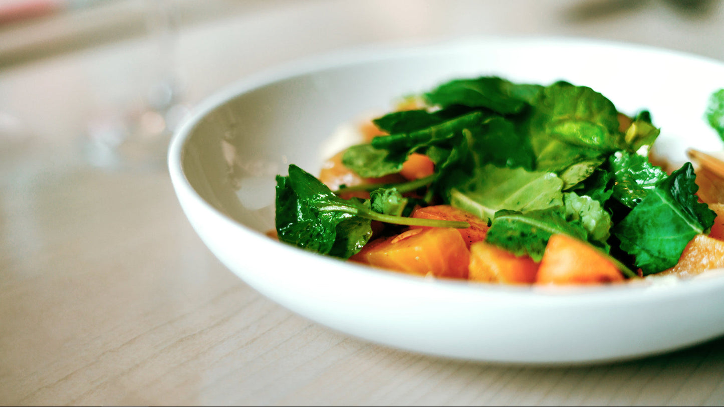 White plate with a salad on a wooden table